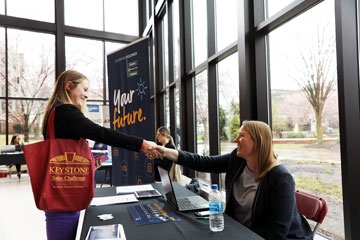 A female student shakes a prospective employers hand during an on-campus job fair