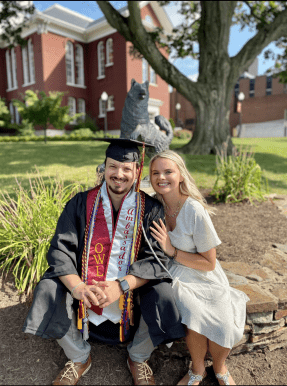 Cole Neff '20 (left) sits in front of the Husky statue with his wife.