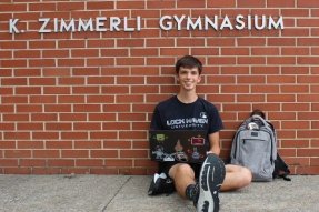 Health and Physical Education student using a lap top outside of Zimmerli Gymnasium on the Lock Haven campus