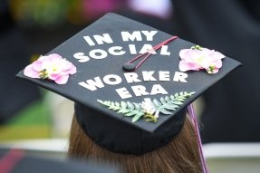 A CU Social Work student's graduation cap says "In My Social Worker Era"