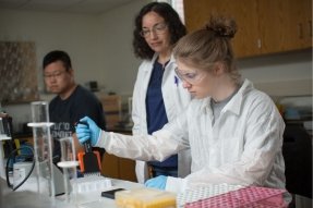 A Chemistry student at CU-Bloomsburg conducting an experiment in a lab while Dr. Toni Bell looks on