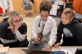 Students and a physician looking at a computer together. 