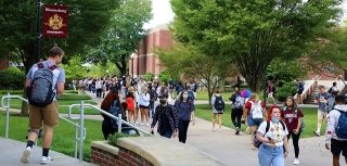 A crowd of people walking around campus. 