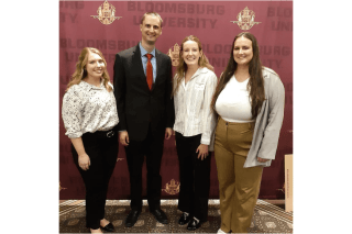 Four people standing together (three girls and a boy).