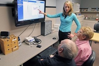 Three people looking at a screen. One of them is pointing to the screen. 