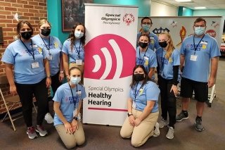 A group surrounding a sign about healthy hearing. 