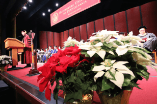 Flowers and two men on the stage with gowns on. 