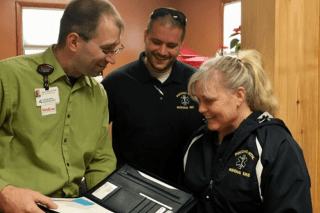 Three people looking at a computer. 