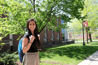 A girl with her backpack standing in front of the school. 