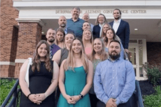 A group of people standing for a photo on a staircase. 