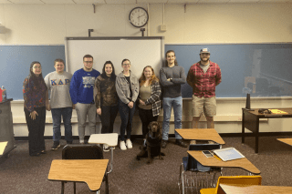 A group of people standing side by side in a classroom. 