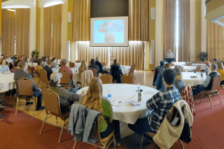 A presentation set up in a large room with tables. 