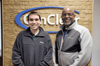 A picture of two men standing in front of a sign.