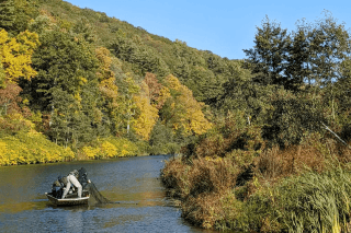 A man on a boat with a net, in a river.