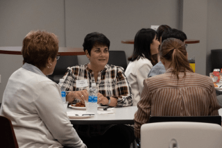 Women pictured at a table talking. 