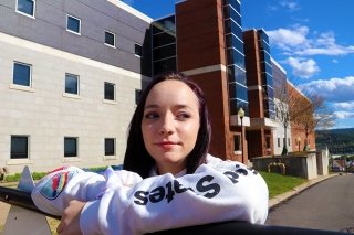 A girl leaning against something outside of a building. 