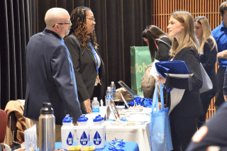 People standing around a vendor table, talking.