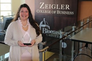 A girl standing in front of the Zeigler College of Business sign. 