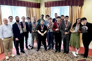 Forensics Team standing in a group with awards. 