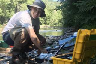 A female in a river with a fishing supplies. 