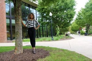 A girl standing by a tree. 