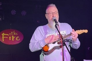 A man playing a guitar and singing.