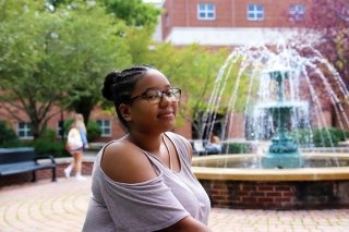 A girl sitting by a fountain. 