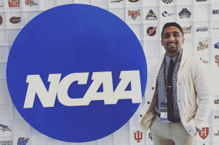 A man standing next to a NCAA sign. 