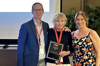 One gentleman and two women pictured holding an award. 