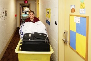 A girl pushing a move in cart down the hall.