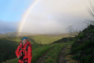 A woman standing in front of a rainbow.