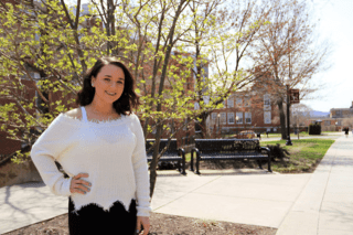 A girl standing in front of the school. 