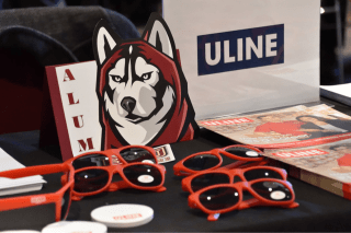 Red sunglasses on a table next to the Bloomsburg mascot. 