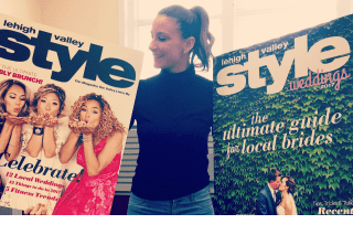 A woman standing with two large magazine covers. 