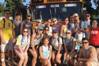 A group of students in front of a bus. 