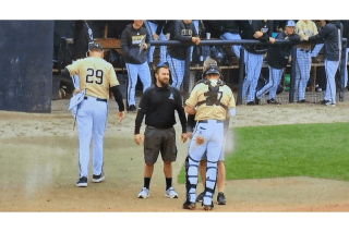 Two baseball players and a coach on a baseball field. 