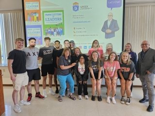 A group standind together in front of a projected screen. 