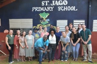 Group of people standing in front of a background that says, "St. Jago Primary School."