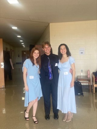 Two girls in blue dresses with a man in a black suit in between them. 