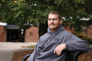 A man leaning back on a bench outside. 