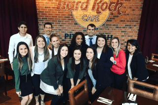 A group of people standing together in front of a brick wall. 