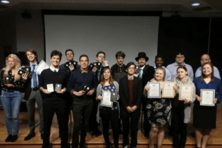 A group of people standing together holding awards. 