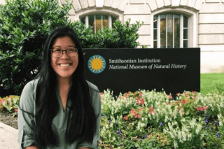 A woman sitting in front of a Smithsonian Institute sign.