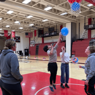 Two children playing with balloons with two adults standing nearby. 