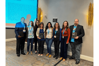 A group of people standing together with awards. 