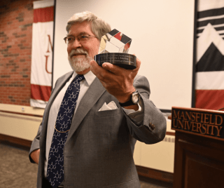 Dr. Kiessling holding an award. 