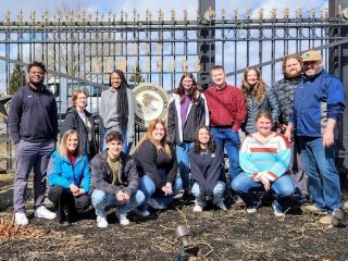 A group of people sitting in front of a fence. 