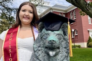 A woman standing next to a husky statue. 