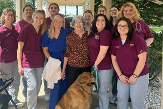 A group of people standing together with a dog. 