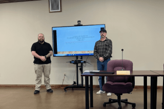 Two people standing next to a smart screen. 